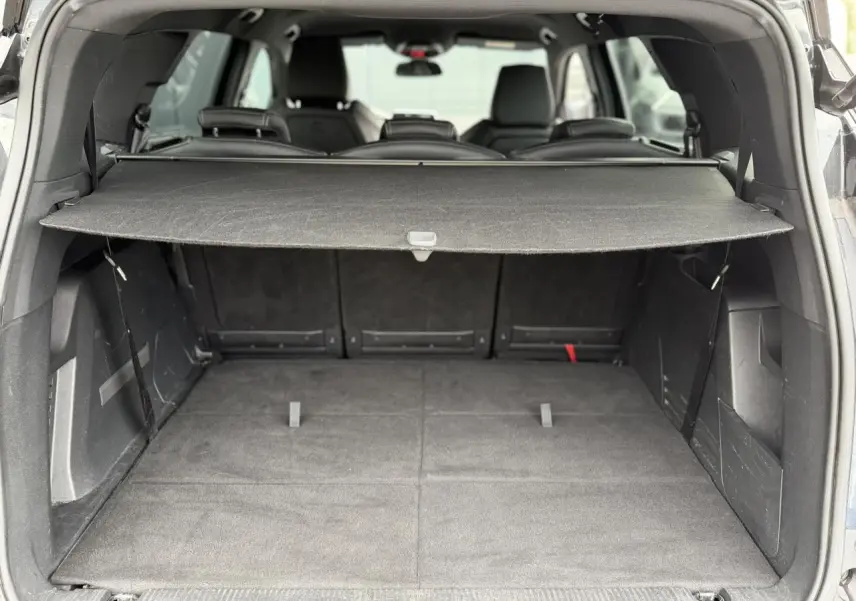 Vue arrière du coffre ouvert du Peugeot 5008 bleu foncé, montrant la plage arrière et les sièges rabattus.