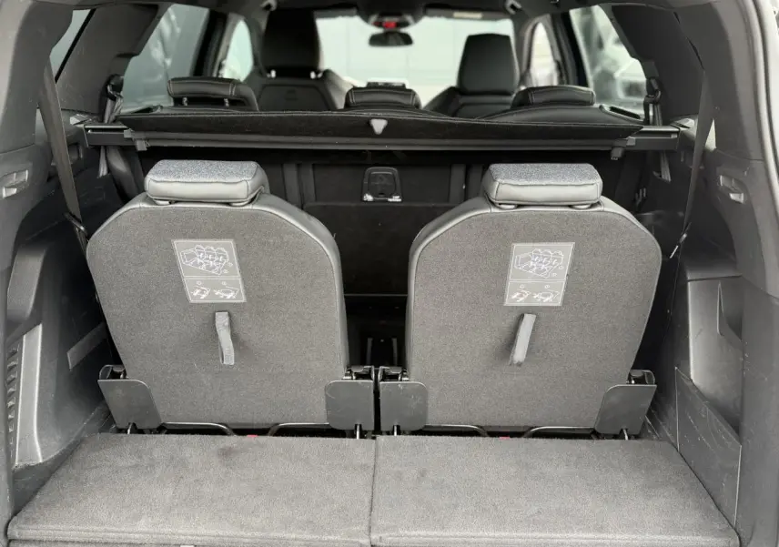 Vue arrière du coffre du Peugeot 5008 bleu foncé avec les deux sièges escamotés de la troisième rangée relevés.
