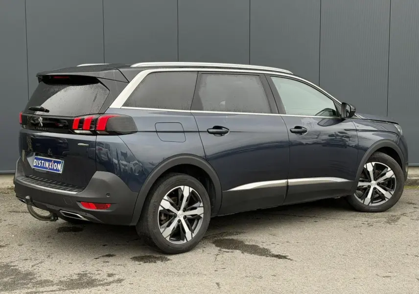 Peugeot 5008 bleu foncé vue 3/4 arrière droit, avec jantes alliage bi-ton et toit noir contrasté.