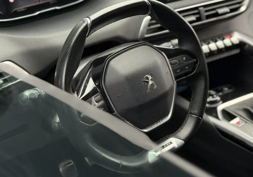 Gros plan sur le volant cuir perforé noir du Peugeot 5008 GT Line 2019 avec tableau de bord et console partiellement visibles.