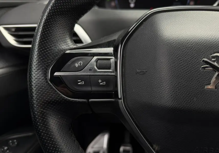 Gros plan sur le volant cuir perforé noir du Peugeot 5008 GT Line avec commandes intégrées côté gauche.