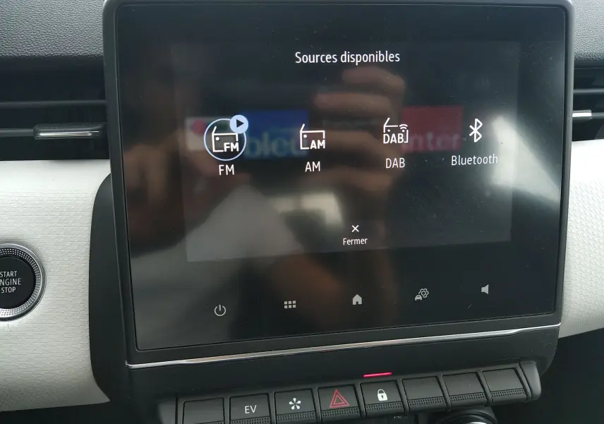 Écran tactile central de la Renault Clio V E-TECH 140ch affichant les sources audio FM, AM, DAB et Bluetooth, intérieur moderne.