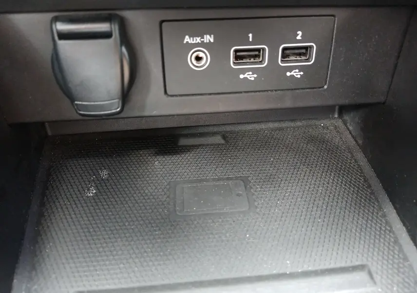 Gros plan sur les ports USB et prise Aux-IN dans l’habitacle noir de la Renault Clio V E-TECH 2022, zone de recharge sans fil visible.