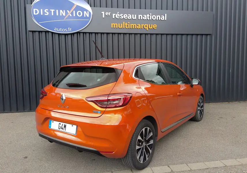 Vue 3/4 arrière droite d'une Renault Clio V E-TECH orange 2022, avec jantes alliage et feux LED distinctifs.