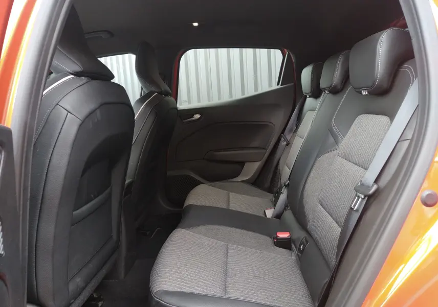 Vue intérieure côté droit des sièges arrière gris et noir de la Renault Clio V E-TECH orange avec porte ouverte.