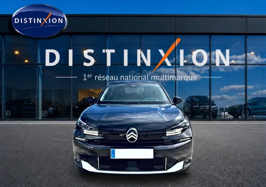Vue avant d'une Citroën C4 X noire 2025, avec calandre distinctive et phares LED, devant une vitrine Distinxion.