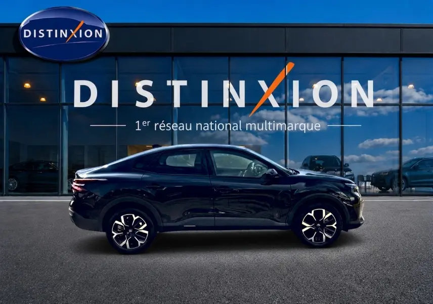 Citroën C4 X noire vue de profil côté gauche, avec jantes alu et silhouette élégante devant une vitrine Distinxion.