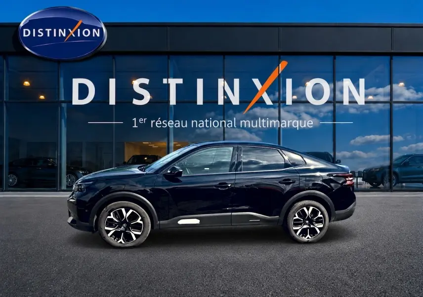 Vue de profil côté gauche d'une Citroën C4 X noire 2025 avec jantes alu et lignes fluides devant une vitrine Distinxion.