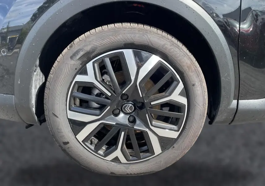 Gros plan sur la jante alu noire et argentée du côté gauche d'une Citroën C4 X noire de 2025.