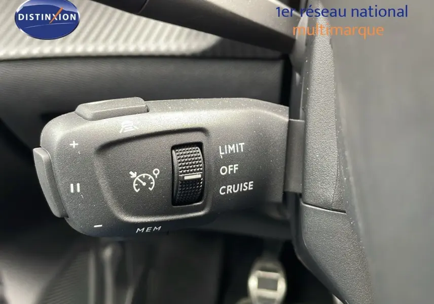 Gros plan sur la commande de régulateur de vitesse du Peugeot 208 gris sélénium avec toit noir, intérieur sombre.