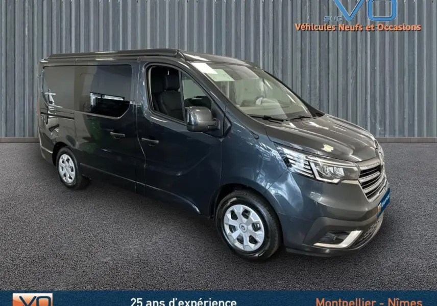 Renault Trafic Fourgon gris en 3/4 avant droit, vitres surteintées et jantes argentées visibles sur fond neutre.