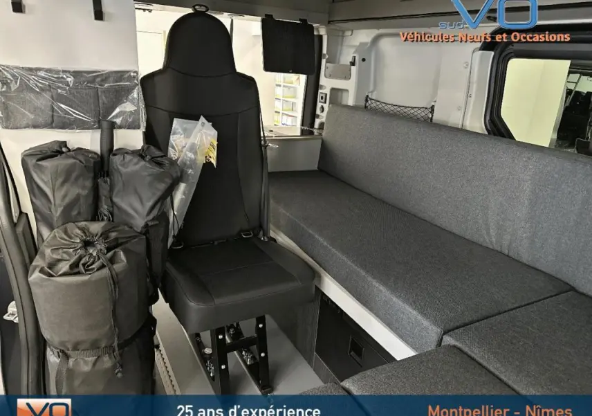 Intérieur du Renault Trafic Fourgon 2025 gris, vue sur siège passager et banquette avec rangements et équipements modulables.