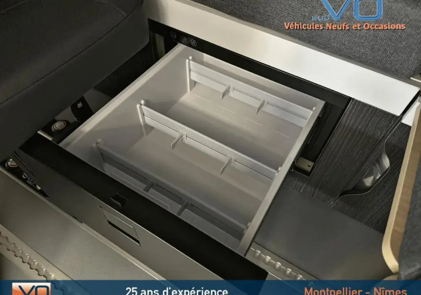 Tiroir de rangement ouvert sous siège dans l'habitacle du Renault Trafic Fourgon gris, version Confort 2025.