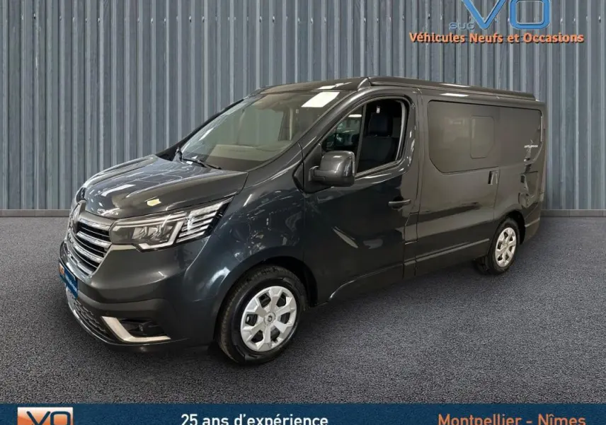 Renault Trafic Fourgon gris en 3/4 avant droit, avec vitres surteintées et jantes argentées visibles en intérieur showroom.