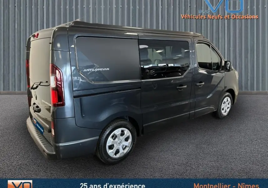 Renault Trafic Fourgon gris en 3/4 arrière droit, vitres surteintées et logo Antilopevan visible sur la porte latérale.