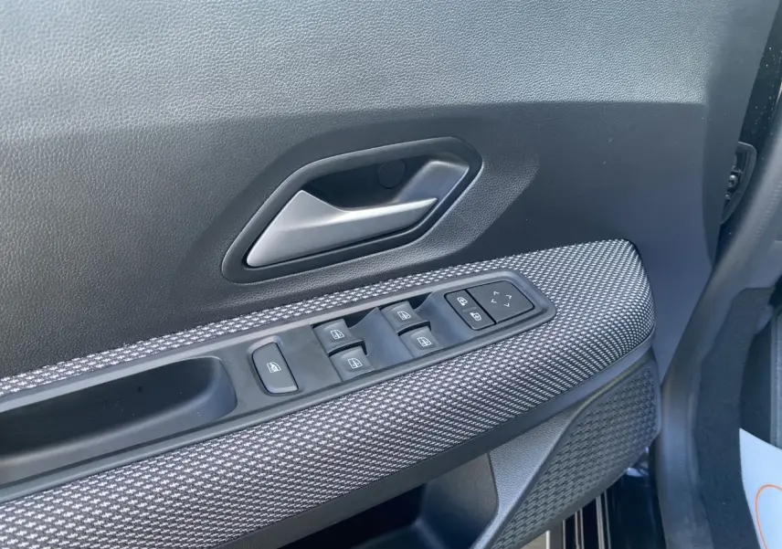 Détail de la porte côté conducteur de la Dacia Sandero Stepway noire avec commandes électriques et habillage tissu noir.