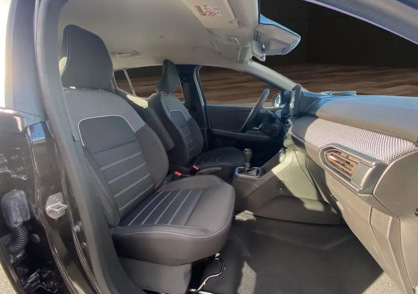 Vue intérieure côté conducteur de la Dacia Sandero Stepway noire 2025, sièges tissu noir et tableau de bord moderne.