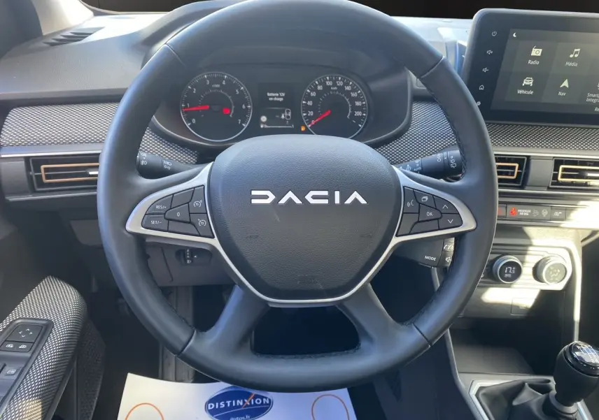 Vue centrée sur le volant noir DACIA avec tableau de bord et écran tactile Media Nav en arrière-plan.