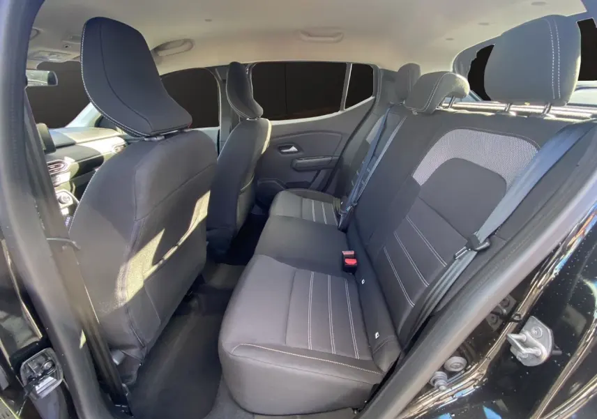 Vue intérieure côté droit arrière de la Dacia Sandero Stepway 2025 noire, montrant les sièges arrière en tissu noir.