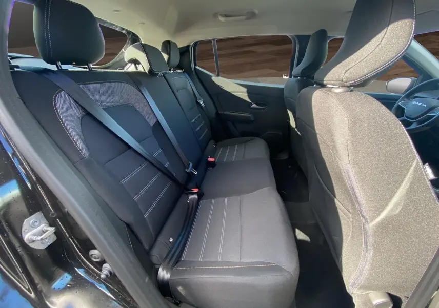 Vue intérieure côté droit des sièges arrière noirs en tissu de la Dacia Sandero Stepway 2025 avec ceinture de sécurité attachée.
