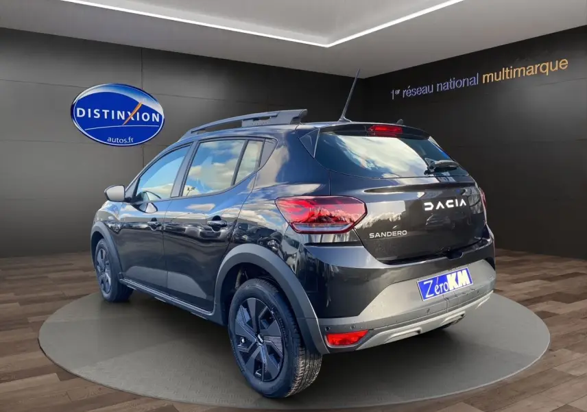 Vue 3/4 arrière droite d'une Dacia Sandero Stepway noire avec barres de toit et feux LED dans un showroom