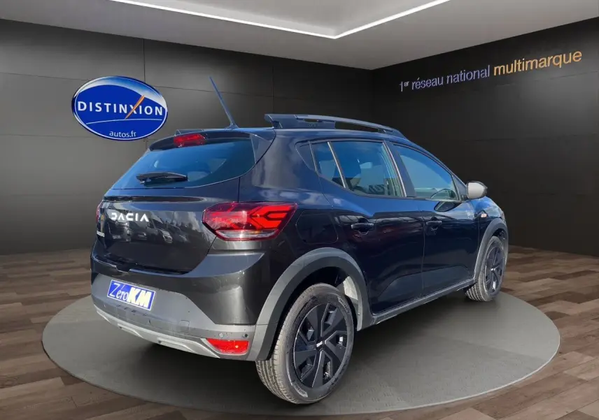 Vue 3/4 arrière droite d'une Dacia Sandero Stepway noire avec barres de toit et feux LED distinctifs.