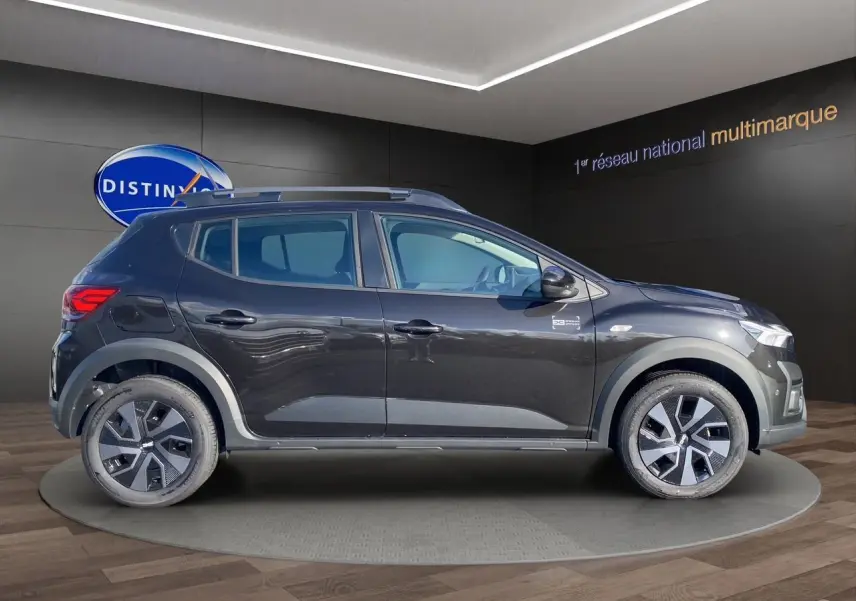 Profil côté gauche d'une Dacia Sandero Stepway noire 2025 avec barres de toit et jantes alliage distinctives.