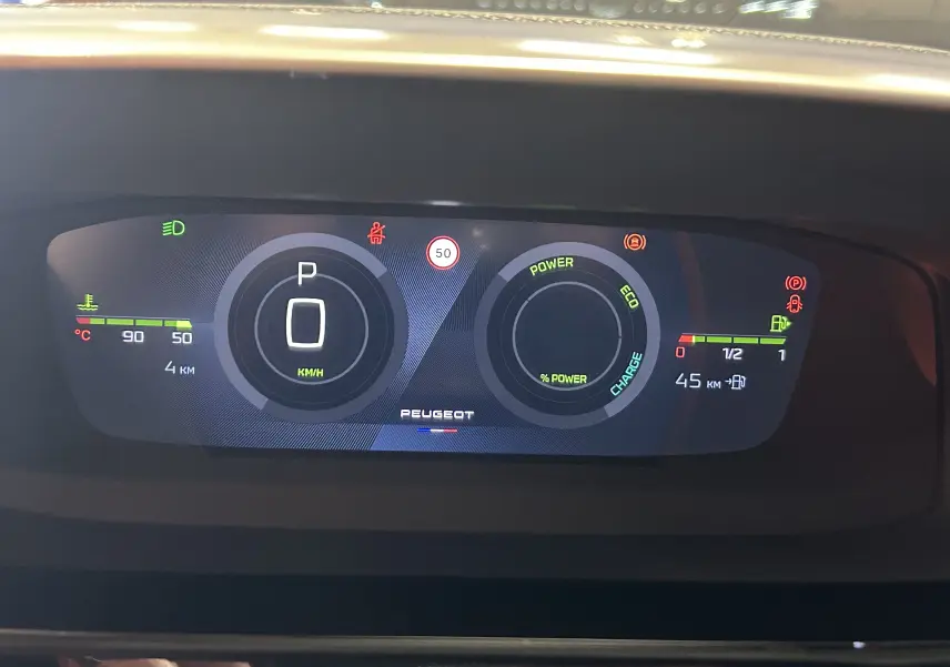 Tableau de bord numérique 3D de Peugeot 308 Hybrid blanc, affichant vitesse, charge et température moteur.