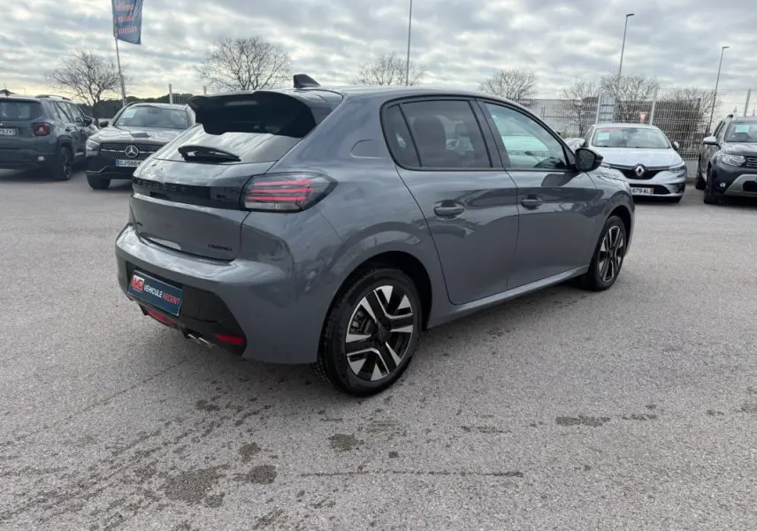 Vue 3/4 arrière droite d'une Peugeot 208 Hybrid 145 gris avec jantes alliage et antenne requin, stationnée en extérieur.