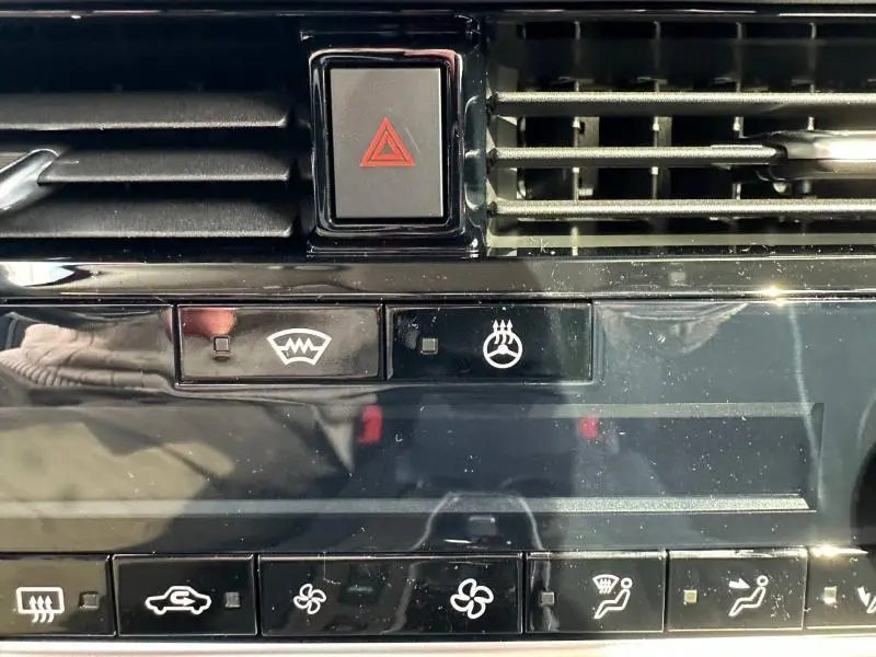 Gros plan sur la console centrale du Nissan Qashqai Hybrid e-POWER 2025 avec boutons de climatisation et signal d’alerte.