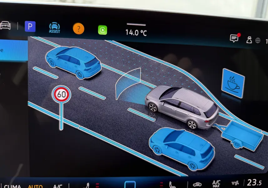 Affichage numérique montrant une Volkswagen Golf SW gris lunaire vue de dessus, entourée de véhicules bleus sur une route virtuelle.