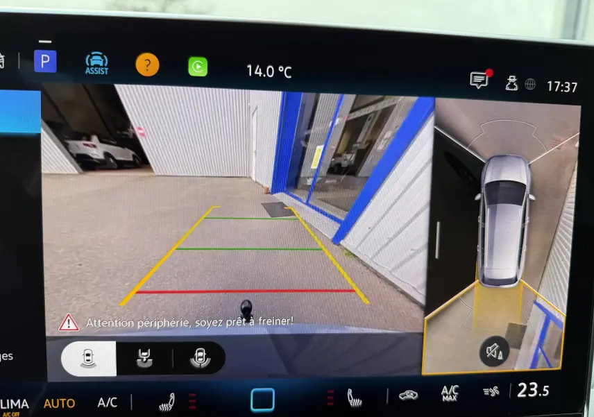 Vue écran caméra de recul et vue aérienne d'une Volkswagen Golf SW gris lunaire en marche arrière près d'un bâtiment.