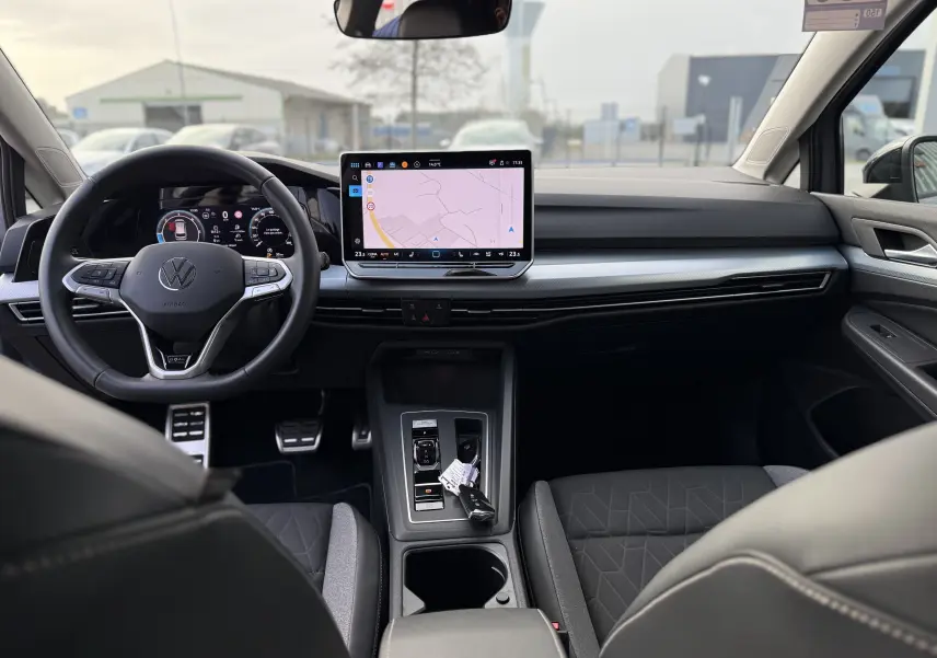 Vue intérieure avant de la Volkswagen Golf SW 2.0 TDI 150 gris lunaire, avec tableau de bord numérique et écran tactile central.