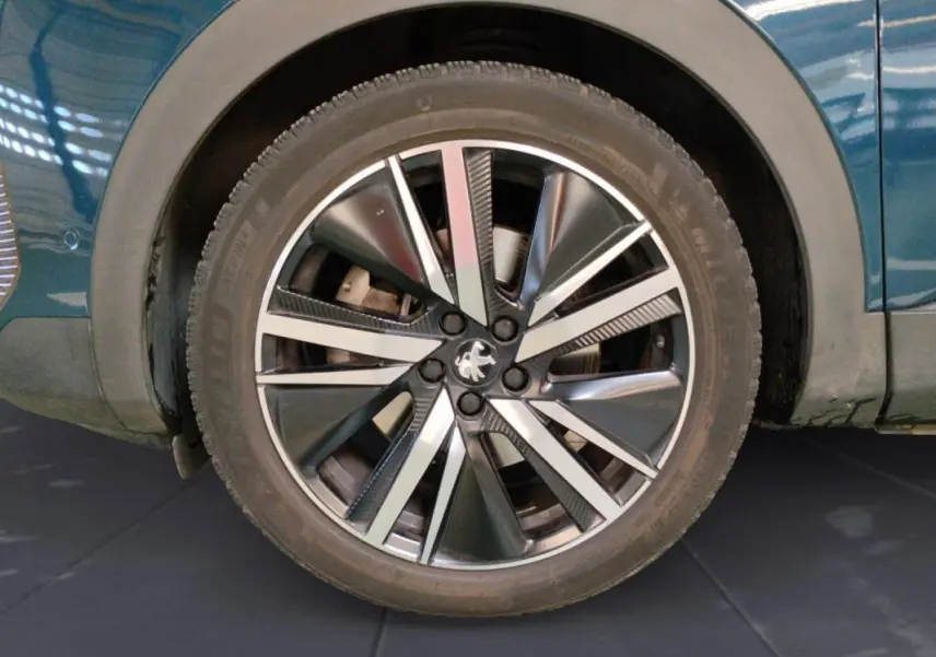 Gros plan sur la roue avant droite du Peugeot 3008 Hybrid 225 e-EAT8 GT Pack bleu clair avec jante alliage 19 pouces.