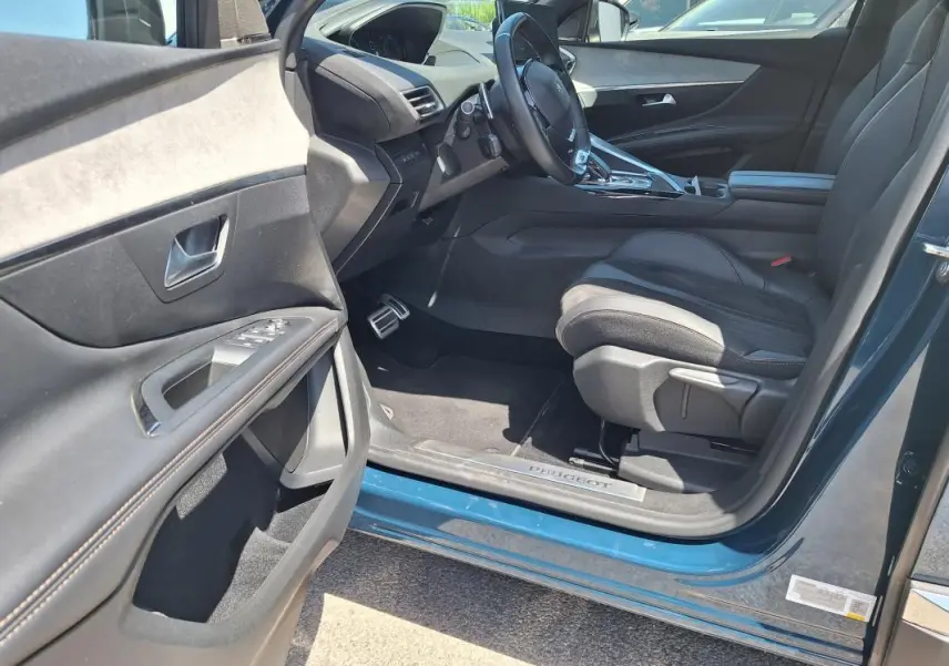 Vue côté conducteur intérieur du Peugeot 3008 Hybrid 225 e-EAT8 GT Pack bleu clair, avec siège en cuir et tableau de bord moderne.