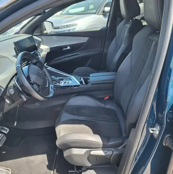 Intérieur avant droit du Peugeot 3008 Hybrid 225 GT Pack bleu clair, sièges cuir noirs et écran tactile visible.