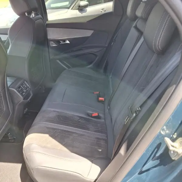 Vue intérieure côté droit des sièges arrière en cuir noir du Peugeot 3008 Hybrid 225 e-EAT8 GT Pack bleu clair, avec ceinture et appuie-tête.