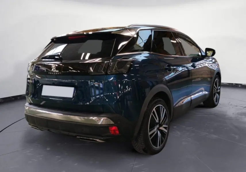 Vue 3/4 arrière droite d’un Peugeot 3008 Hybrid 225 e-EAT8 GT Pack bleu foncé avec jantes alliage 19 pouces et barres de toit.