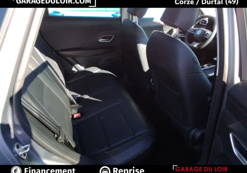 Vue intérieure côté arrière gauche du MG ZS 1.5L Hybrid+ Luxury 2025, sièges cuir noirs et tableau de bord partiel visible.