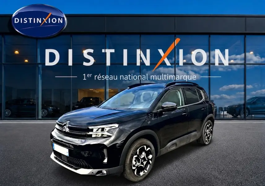 Citroën C5 Aircross noir vue 3/4 avant droit, avec jantes alu distinctives et barres de toit visibles.