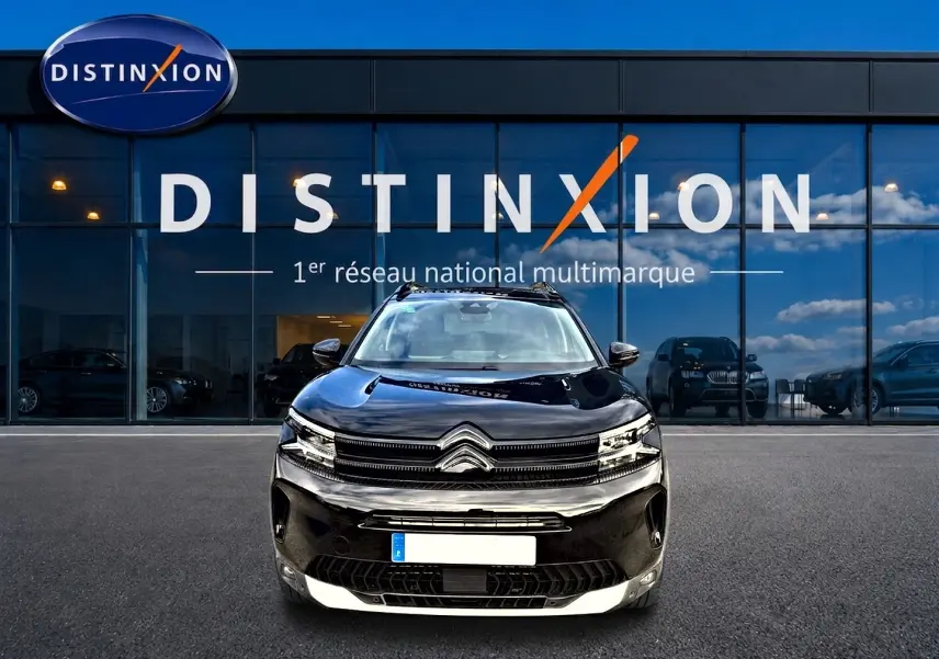 Vue avant d'un Citroën C5 Aircross noir 2025, avec calandre distinctive et phares LED, devant un showroom Distinxion.