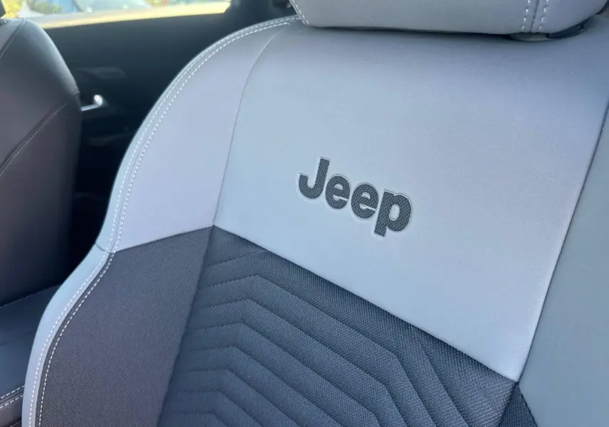 Gros plan sur le siège avant gris et noir du Jeep Compass 2026 avec logo Jeep brodé, intérieur moderne et soigné.