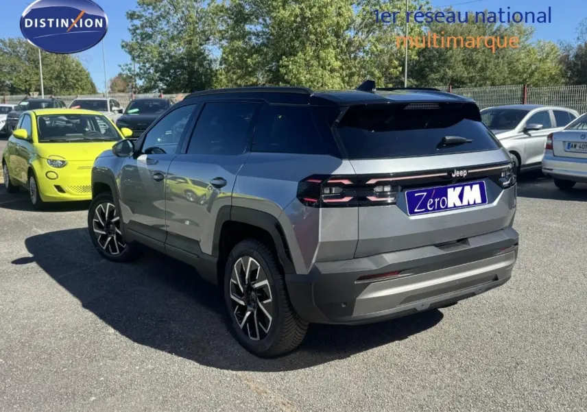 Jeep Compass Yosemite gris avec toit noir, vue 3/4 arrière côté gauche sur parking en extérieur.