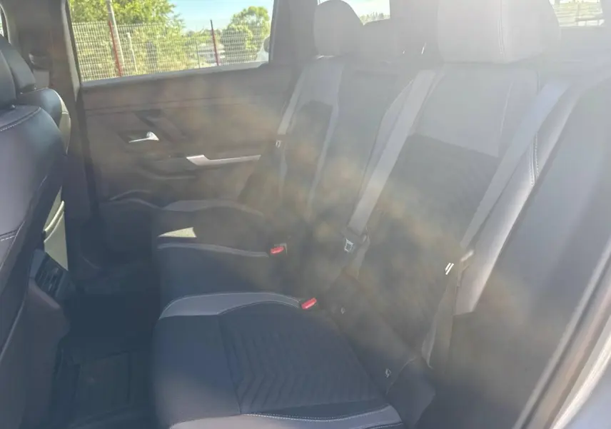 Vue latérale intérieure arrière du Jeep Compass 2026 avec sièges tissu noir et surpiqûres claires, ceintures grises visibles.