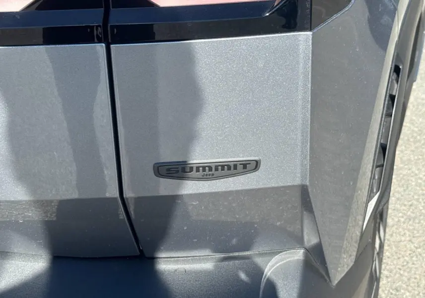 Gros plan sur l’écusson Summit noir sur la portière côté droit d’un Jeep Compass Yosemite gris métallisé.