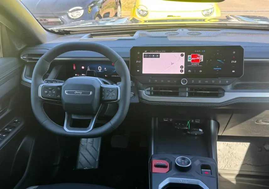 Vue intérieure frontale du Jeep Compass 2026, tableau de bord noir avec écran tactile large et volant multifonctions.