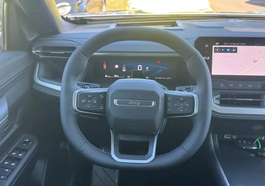 Vue intérieure frontale du volant noir du Jeep Compass 2026 avec tableau de bord numérique et écran tactile.