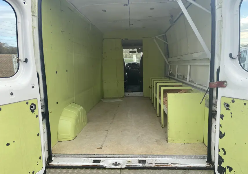 Vue intérieure arrière du Citroën Jumper blanc 2011 avec aménagements verts usés et plancher en bois.