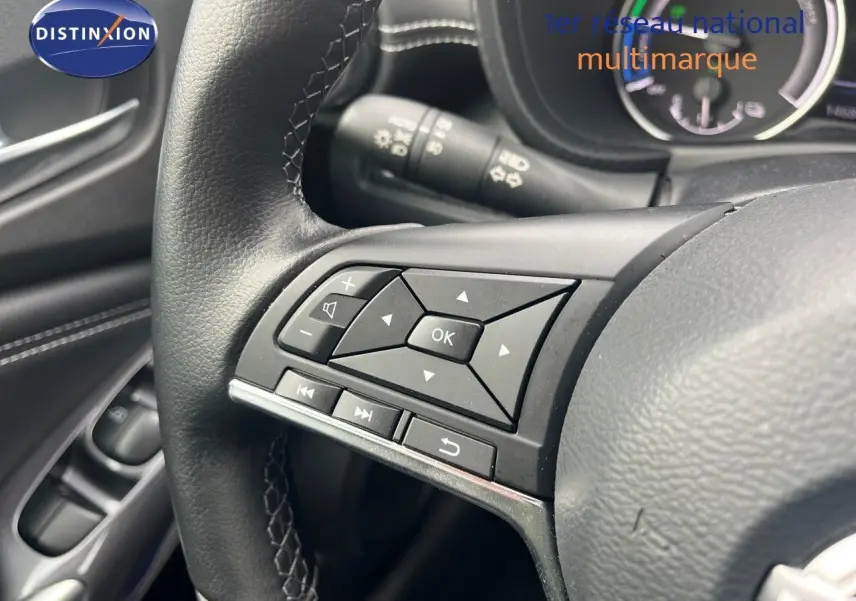 Gros plan sur les commandes multifonctions du volant en cuir noir du Nissan Juke blanc nacré 2024.