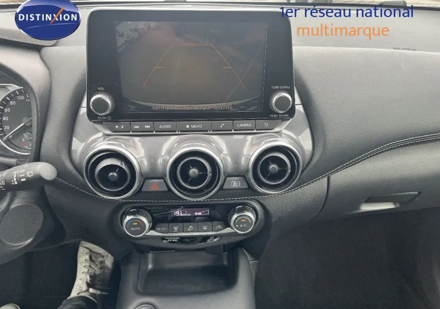 Tableau de bord du Nissan Juke blanc nacré 2024, vue frontale centrée sur l'écran tactile et les aérateurs ronds.